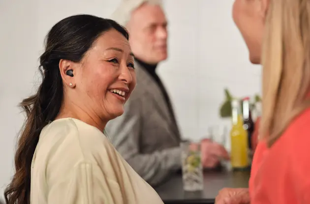 A woman with a headset on smiling at someone.