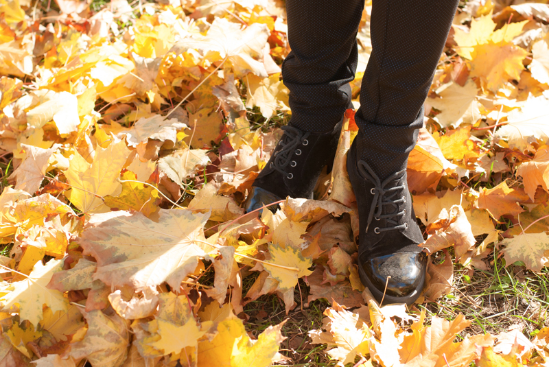 A person in black boots standing on leaves.